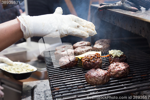 Image of Beef burgers being grilled on food stall grill.