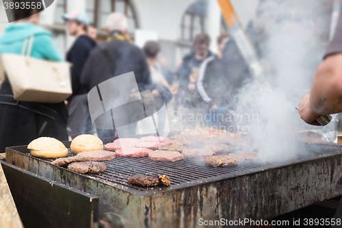 Image of Beef burgers being grilled on food stall grill.