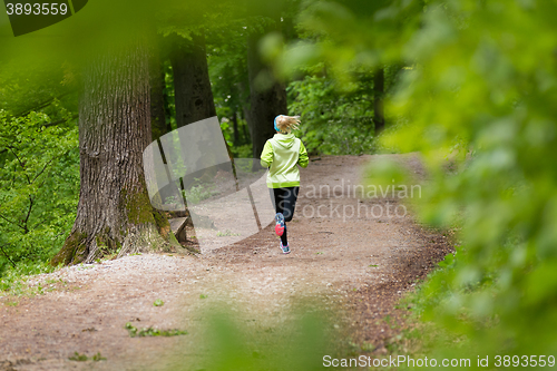 Image of Sporty young female runner in the forest. 