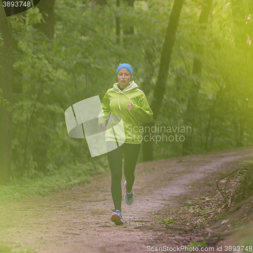 Image of Sporty young female runner in the forest. 