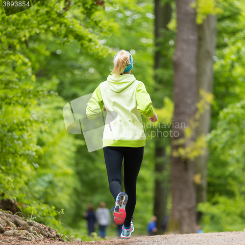 Image of Sporty young female runner in the forest. 