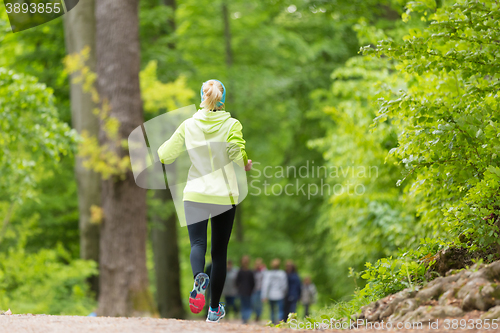 Image of Sporty young female runner in the forest. 