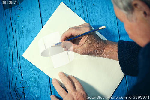 Image of Senior man with blank white paper sheet and pencil