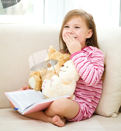 Image of Little girl is reading a book for her teddy bears