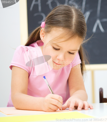 Image of Little girl is writing using a pen