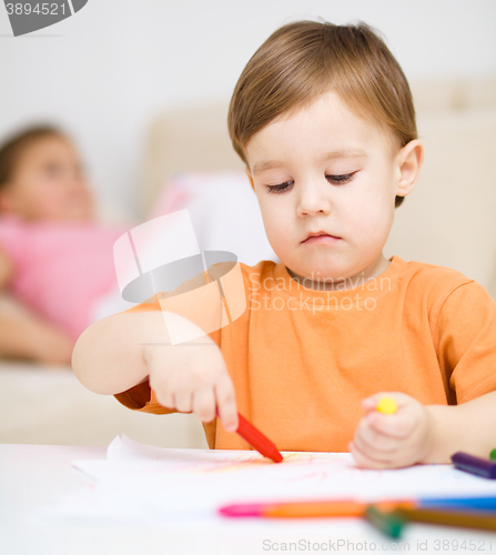 Image of Little boy is drawing on white paper