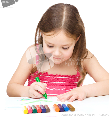 Image of Little girl is drawing using colorful crayons