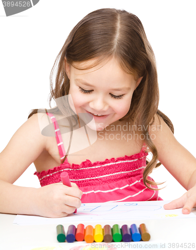 Image of Little girl is drawing using colorful crayons