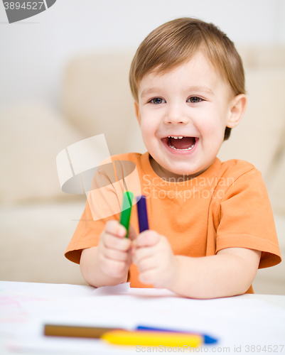 Image of Little boy is drawing on white paper