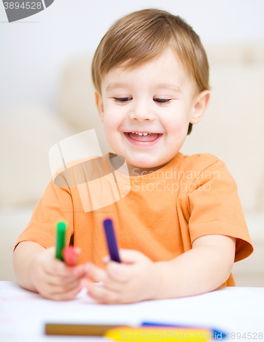 Image of Little boy is drawing on white paper