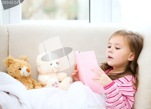 Image of Little girl is reading a story for her teddy bears