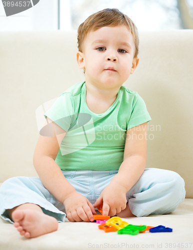 Image of Boy is playing while sitting on couch