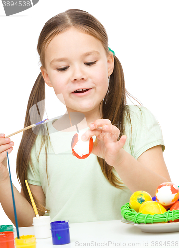 Image of Little girl is painting eggs preparing for Easter
