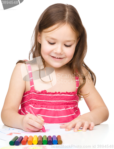 Image of Little girl is drawing using colorful crayons