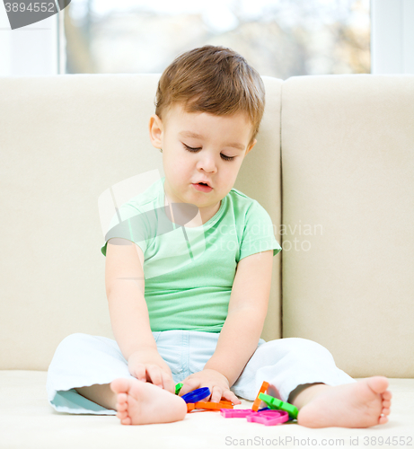 Image of Boy is playing while sitting on couch