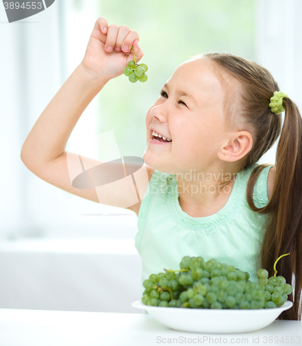 Image of Cute little girl is looking at green grapes