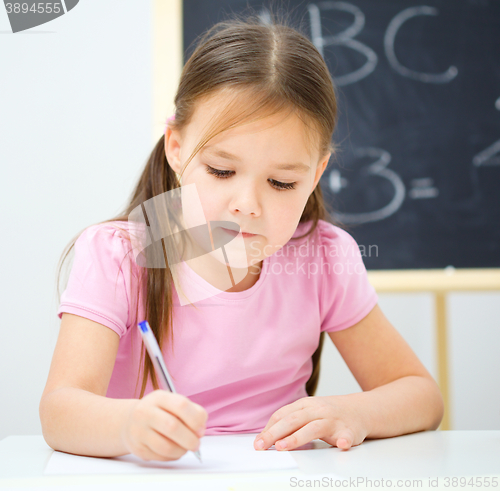 Image of Little girl is writing using a pen