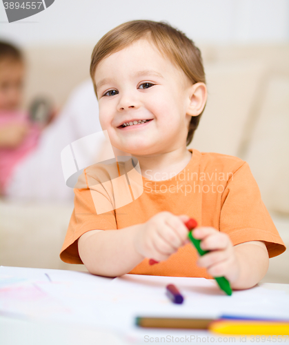 Image of Little boy is drawing on white paper