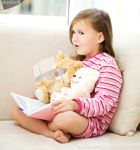 Image of Little girl is reading a story for her teddy bears