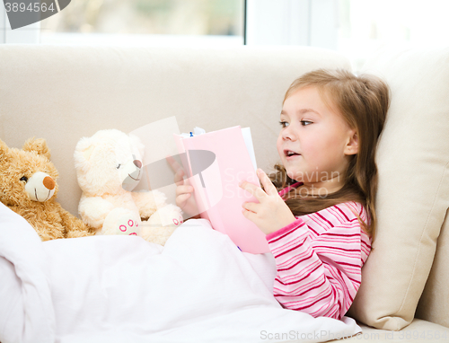 Image of Little girl is reading a book for her teddy bears