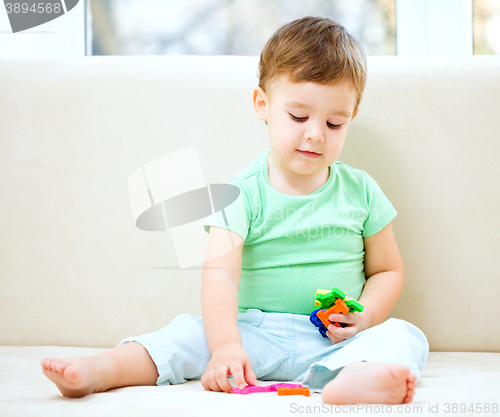 Image of Boy is playing while sitting on couch