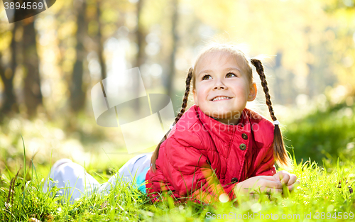 Image of Cute little girl is playing with leaves in park