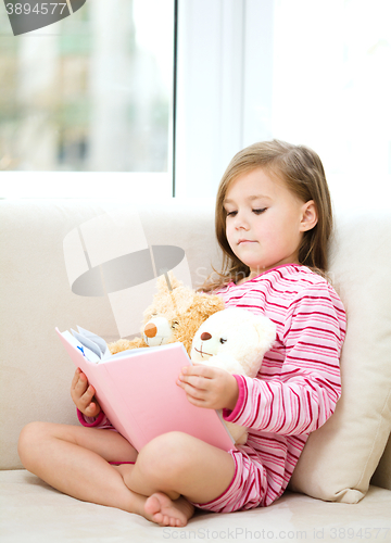 Image of Little girl is reading a story for her teddy bears