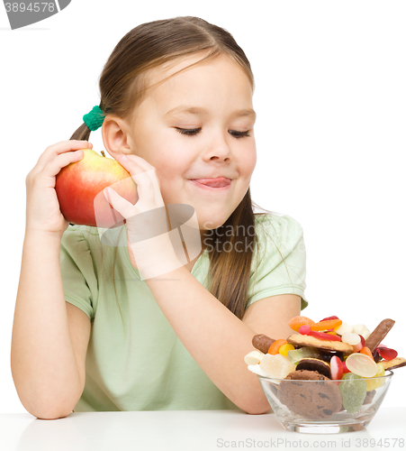 Image of Little girl choosing between apples and sweets