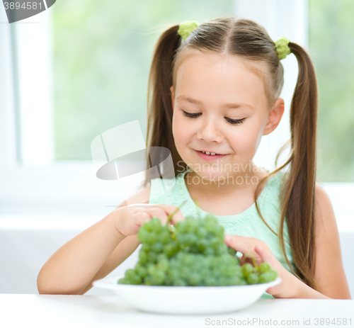 Image of Cute little girl is eating green grapes