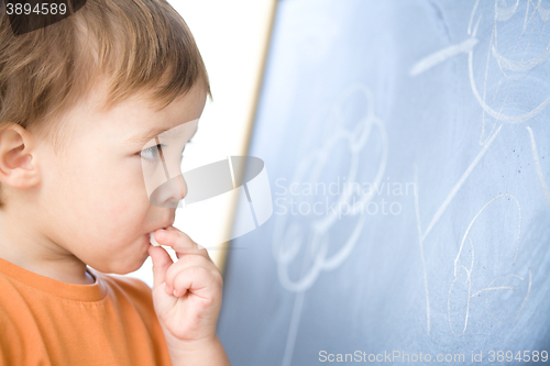 Image of Little boy is biting chalk