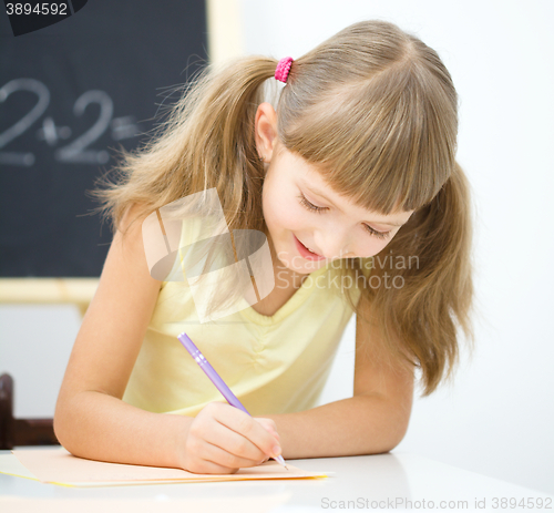 Image of Little girl is writing using a pen