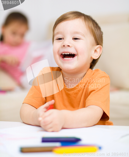 Image of Little boy is drawing on white paper