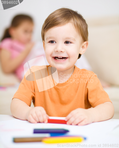 Image of Little boy is drawing on white paper