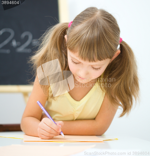 Image of Little girl is writing using a pen