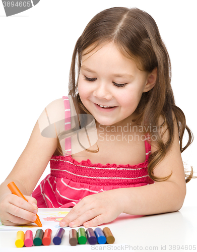 Image of Little girl is drawing using colorful crayons