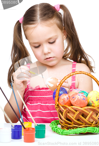 Image of Little girl is painting eggs preparing for Easter