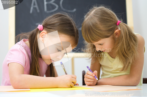 Image of Little girls are writing using a pen