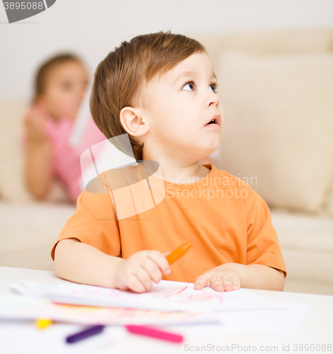 Image of Little boy is drawing on white paper