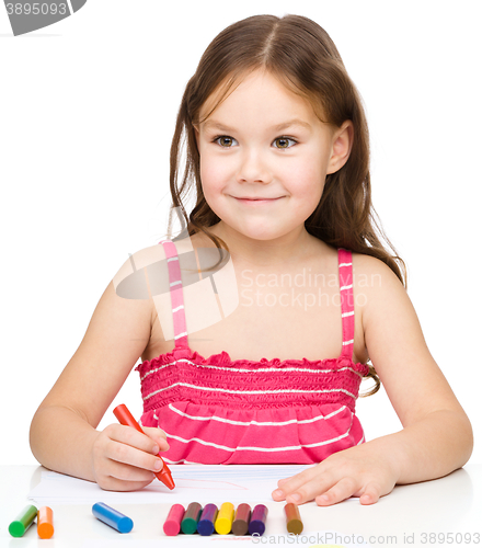 Image of Little girl is drawing using colorful crayons