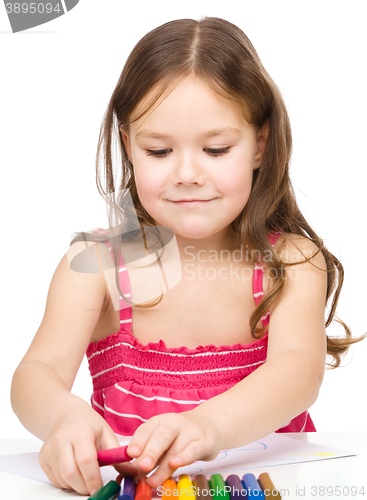 Image of Little girl is drawing using colorful crayons