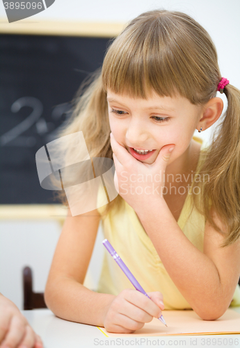 Image of Little girl is writing using a pen