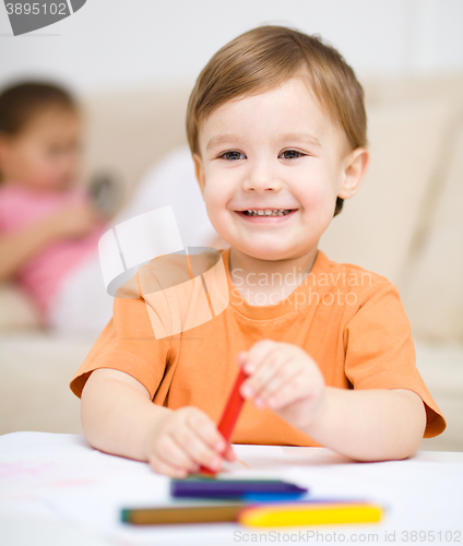 Image of Little boy is drawing on white paper