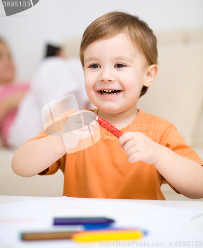 Image of Little boy is drawing on white paper