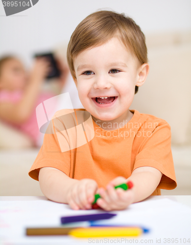 Image of Little boy is drawing on white paper