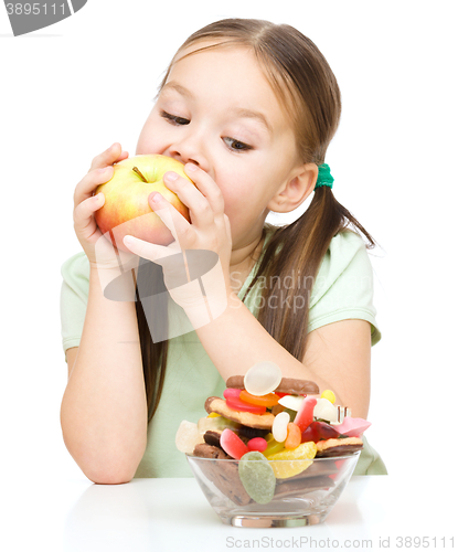 Image of Little girl choosing between apples and sweets