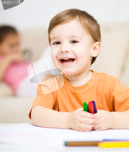 Image of Little boy is drawing on white paper