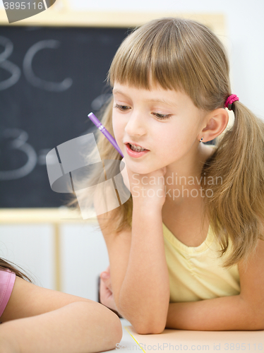 Image of Little girl is writing using a pen