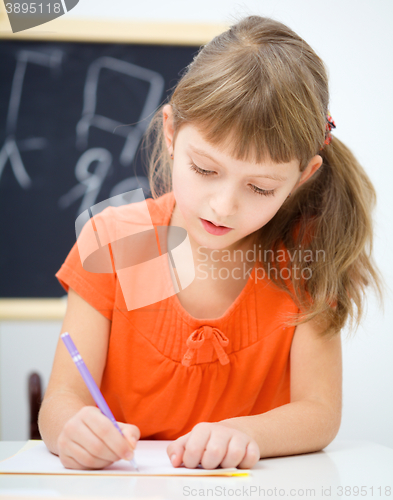 Image of Little girl is writing using a pen