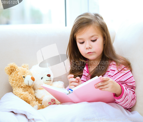 Image of Little girl is reading a story for her teddy bears