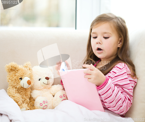 Image of Little girl is reading a story for her teddy bears